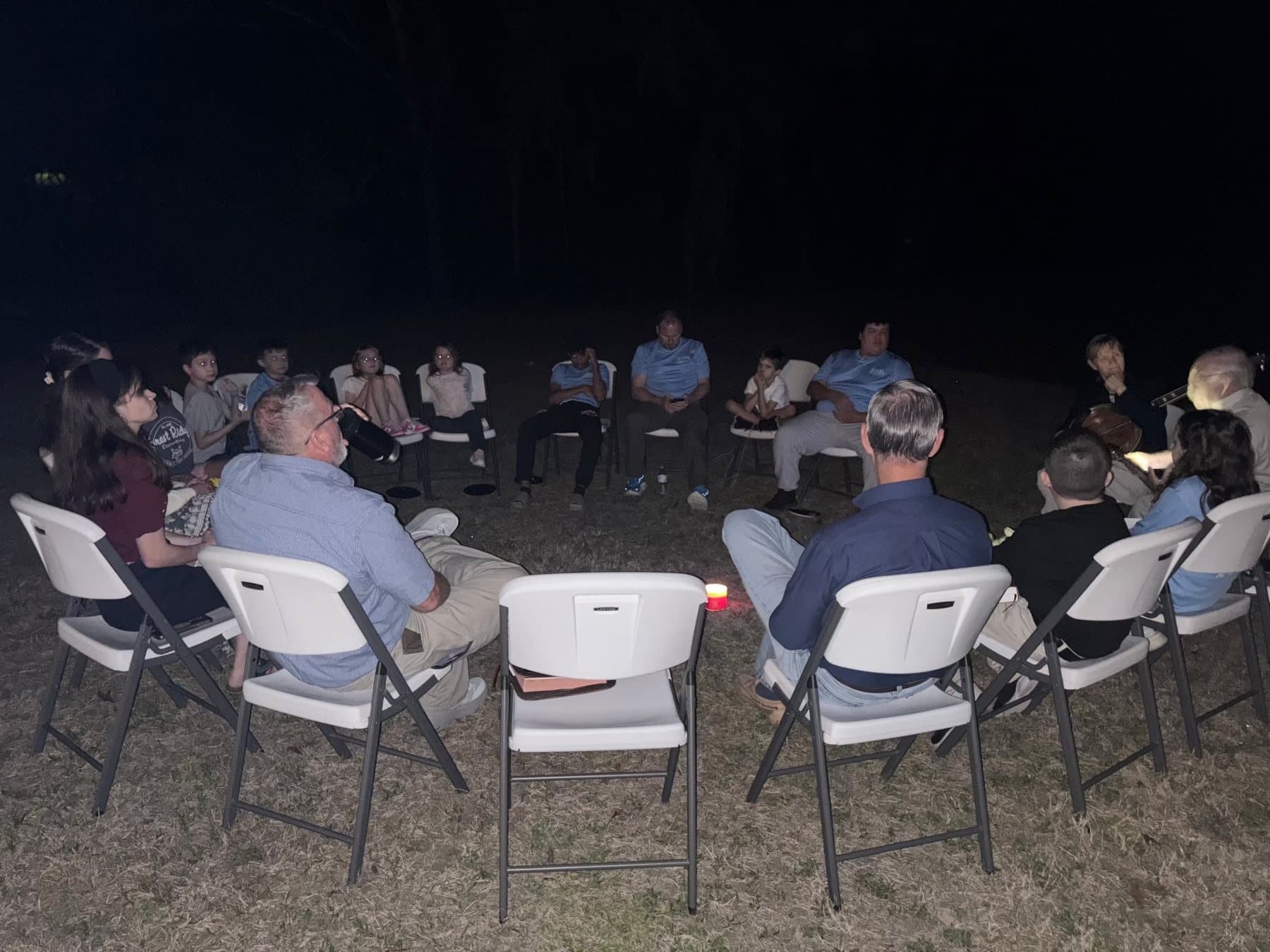 The church in folding chairs around a campfire at night