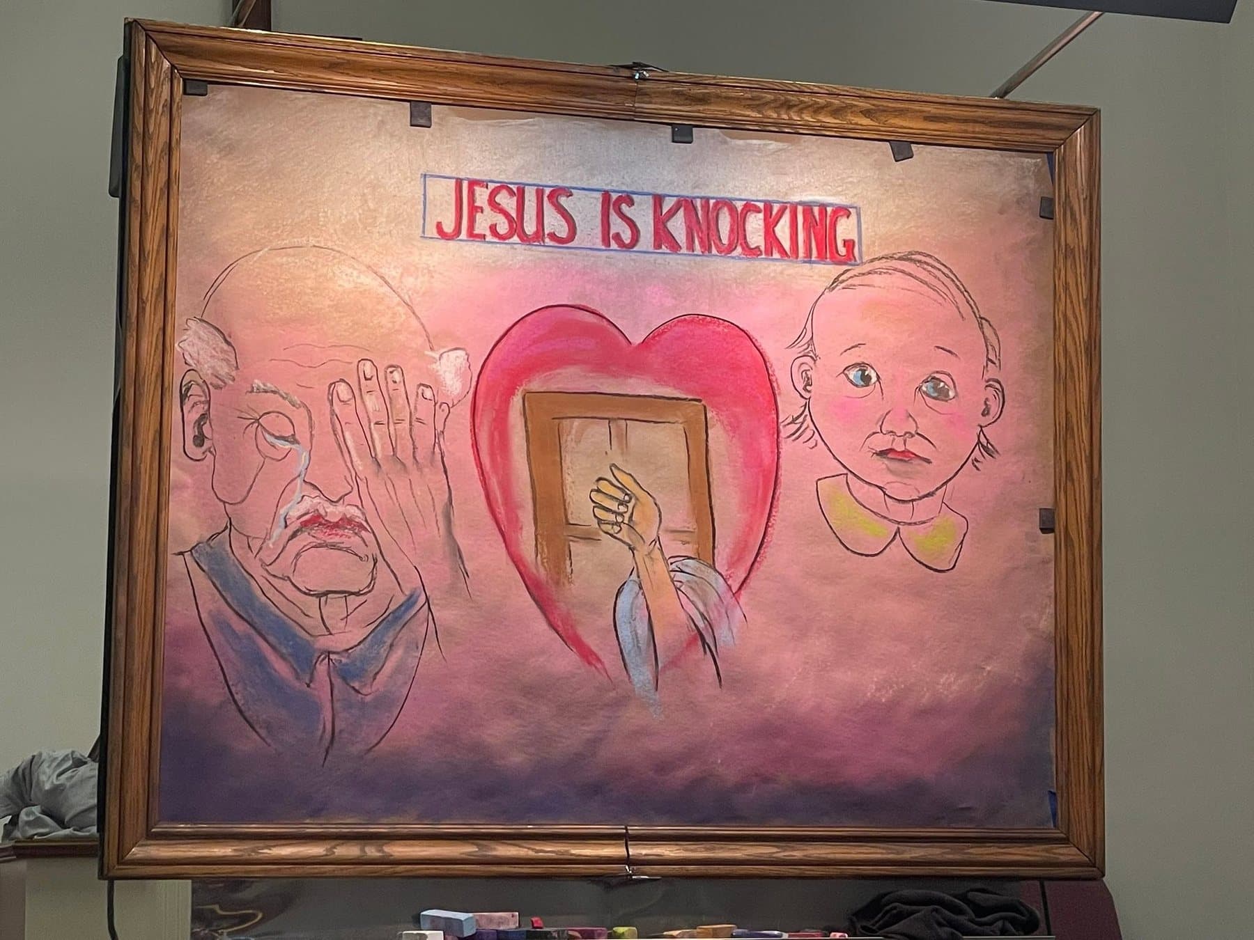 A chalk artist’s finished drawing, Jesus is Knocking, on an easel in the sanctuary