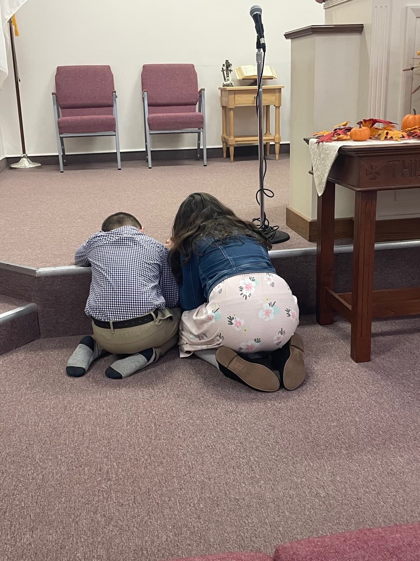 Children kneeling together in prayer at the front of the sanctuary