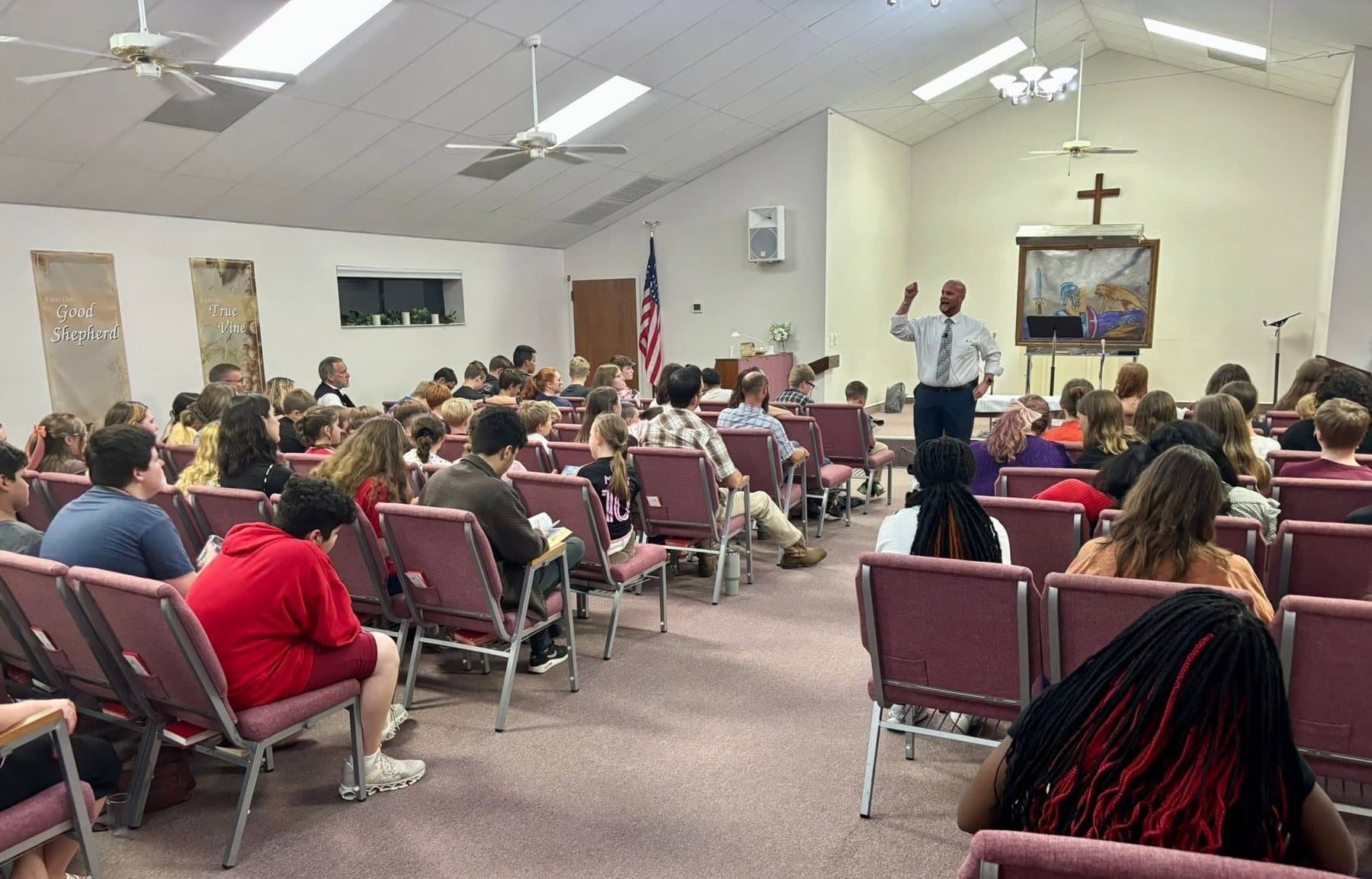 The congregation in the burgundy chairs during a service, Pastor Bankert at the pulpit