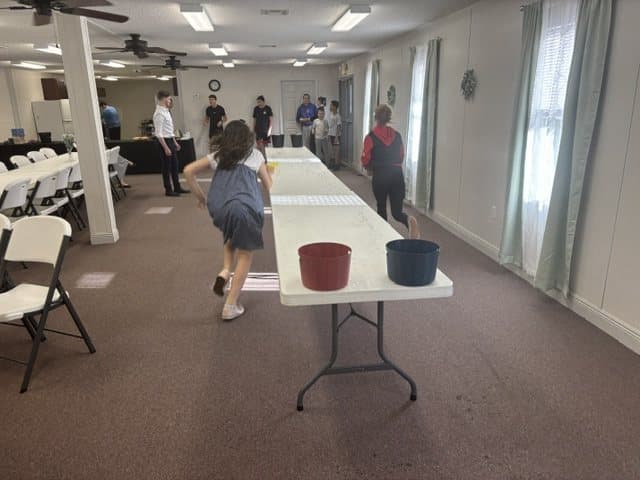 Two children racing with buckets down the fellowship hall