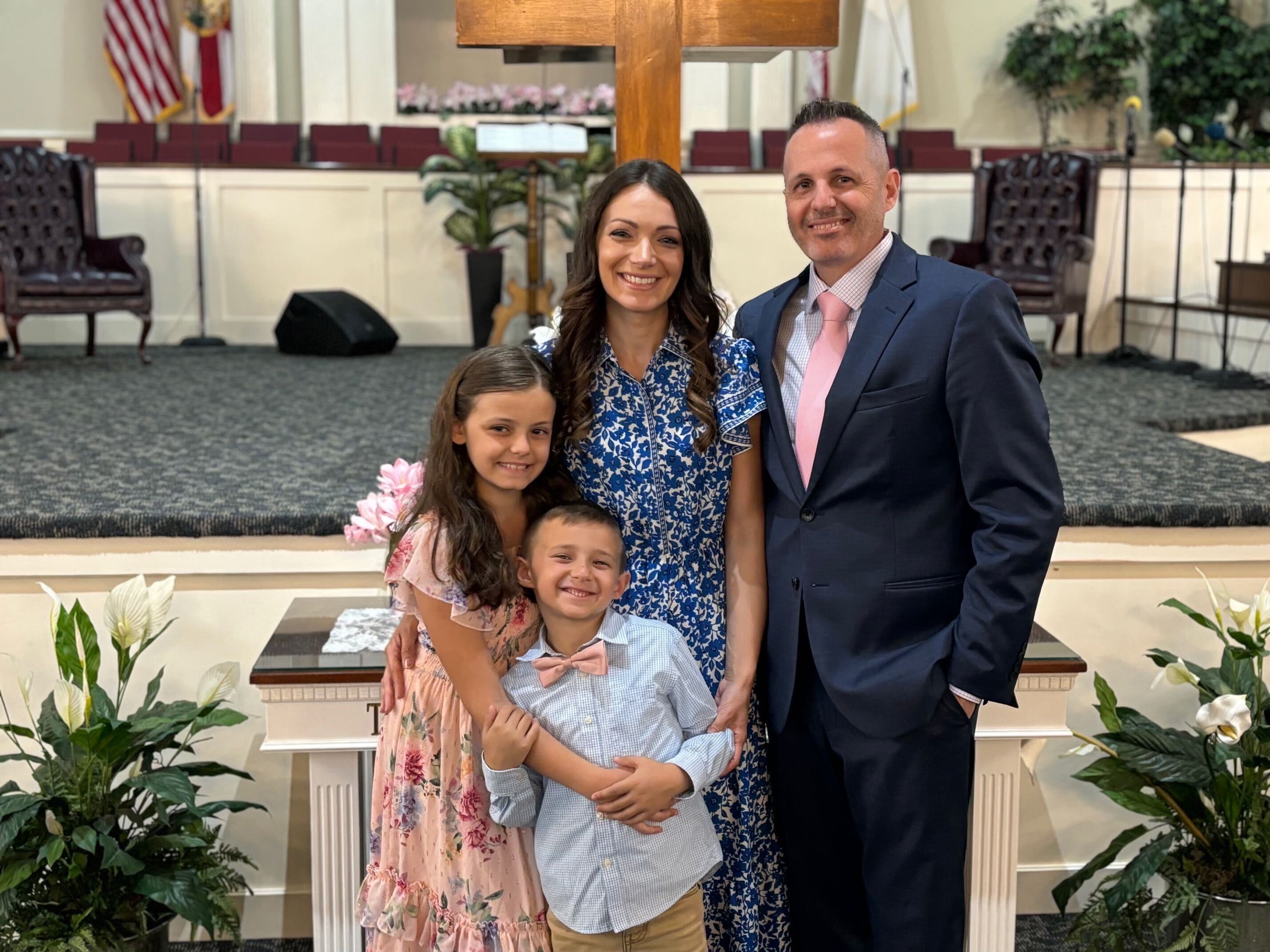 Pastor Brandon Bankert with his wife and their three children in front of the cross at Bethel Baptist Church