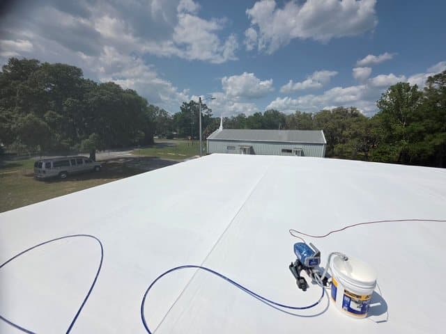 On the roof: a fresh white coating going on under a blue Florida sky