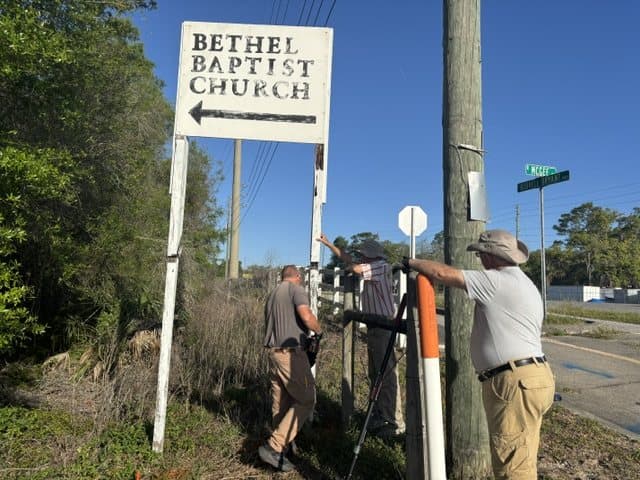 Men taking down the old rusted road sign